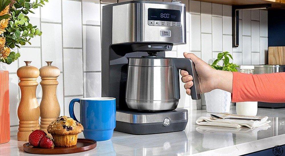 hand putting coffee pot into coffee maker within a kitchen setting